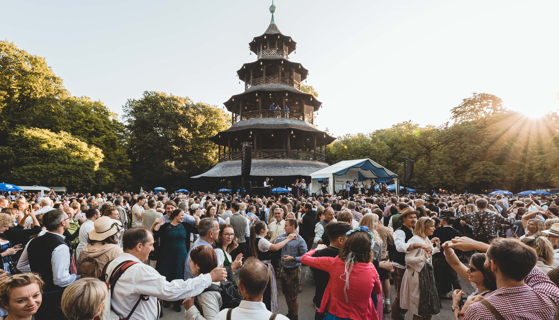 Große Menschenmenge tanzt dicht gedrängt um den Chinesischen Turm und eine Musikkapelle spielt